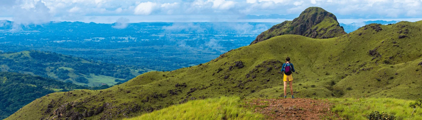 A backpacker girl admires the skyline of Costa Rica's Cerro Pelado mountains during a sunny day