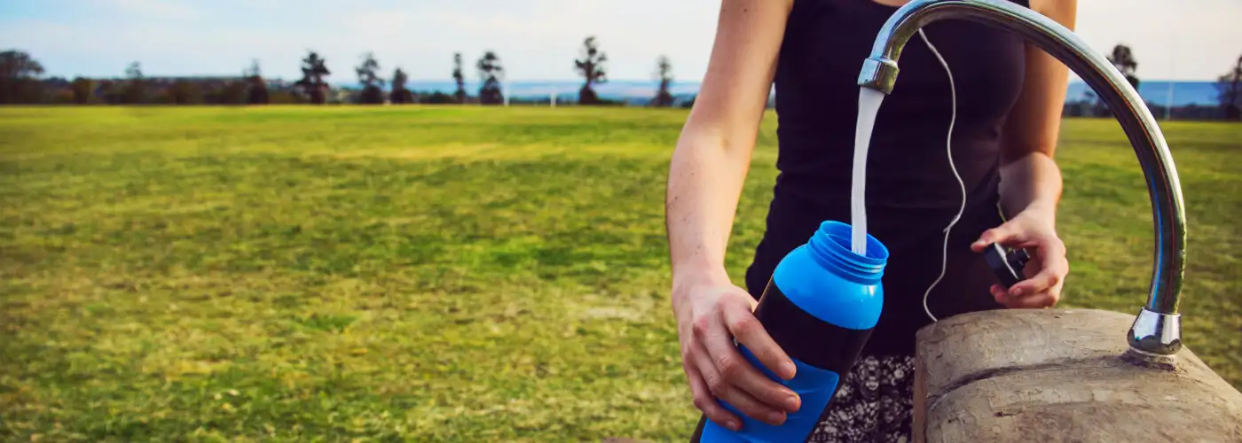 Person filled water bottle out of faucet in the middle of a field