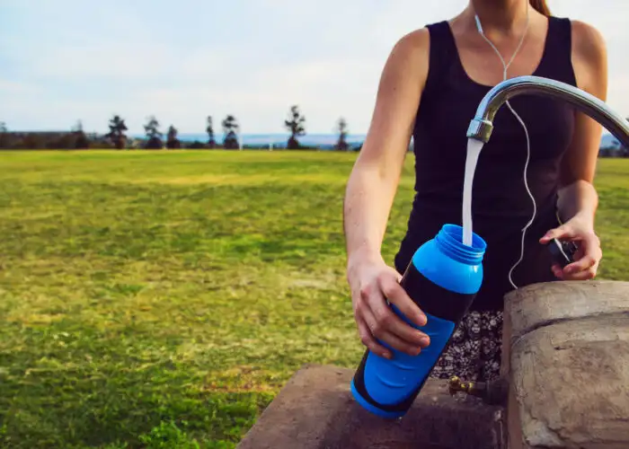 Person filled water bottle out of faucet in the middle of a field