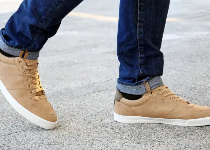 Close-up of man wearing tan sneakers and crossing the street