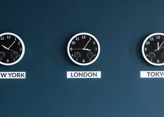 Three clocks on a dark blue wall showing the times in New York, London, and Tokyo