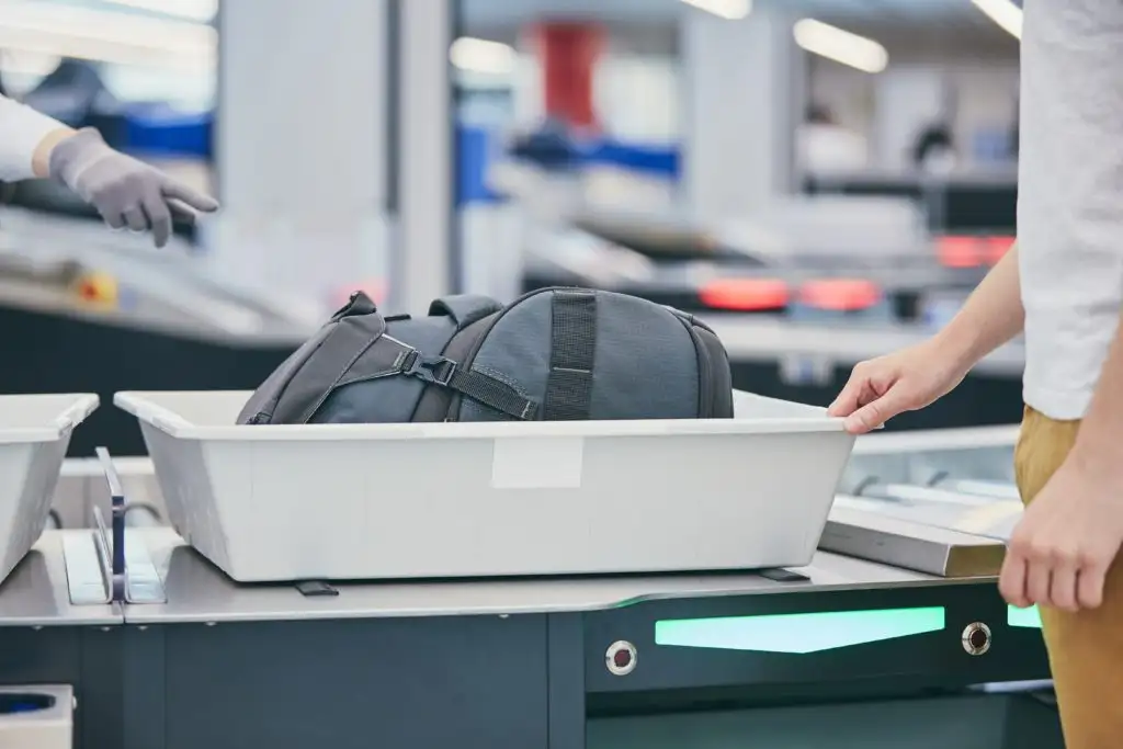 Person placing their backpack in an airport security bin