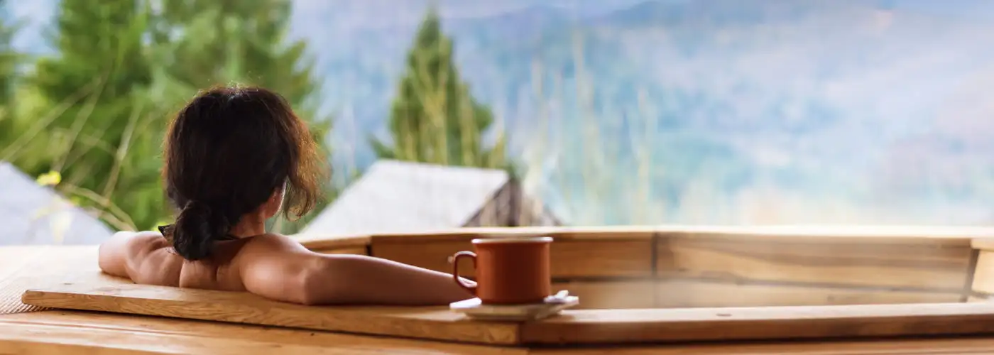 Woman in wooden hot tub with a view of the mountains