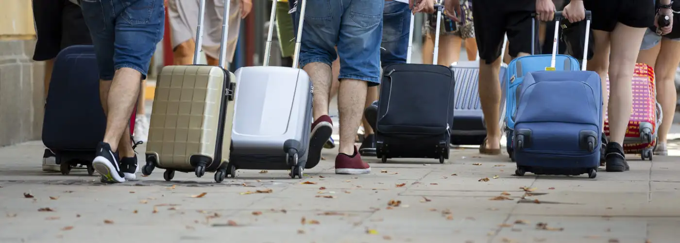 People pulling rolling suitcases in large crowd