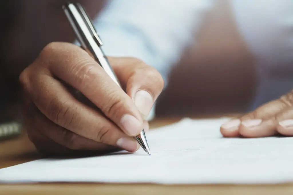 Close up of woman's hands writing in notebook with pen