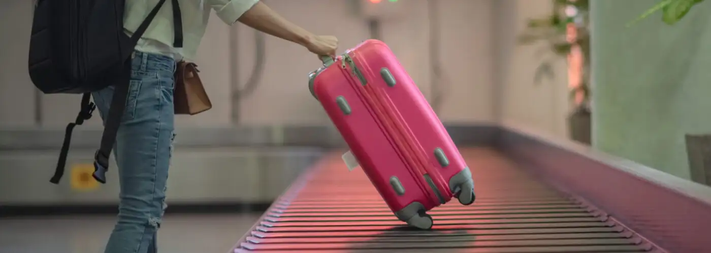 Person collecting the last suitcase from an empty baggage carousel in the airport