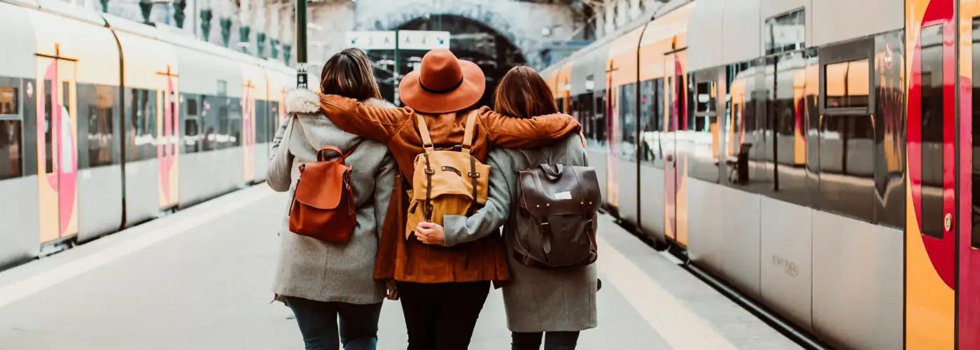 Three friends facing away from camera at train station