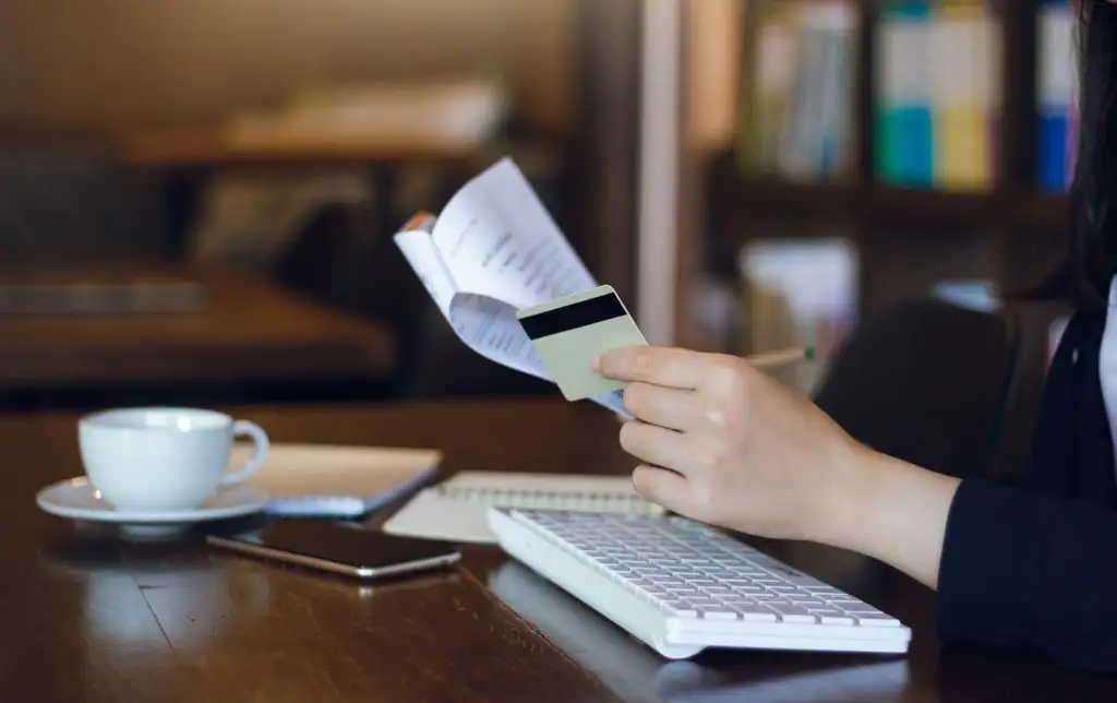 Close up of person going through their credit card statement with a cup of coffee next to a keyboard