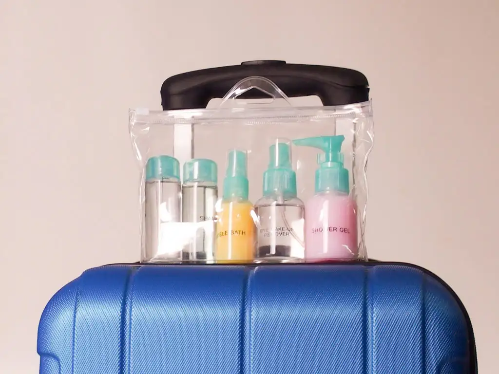 Clear plastic bag with TSA compliant liquid containers on top of a rolling carry on