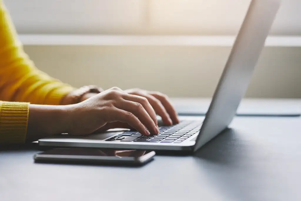 Close up of person's hands as they type on a laptop