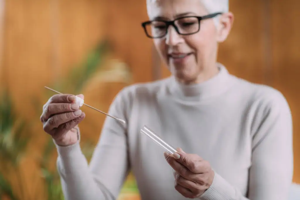 Woman taking a genetic test at home, placing a cotton swap in a test tube