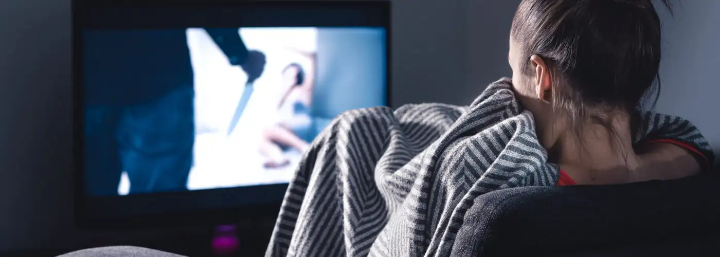 Woman watching scary movie on screen