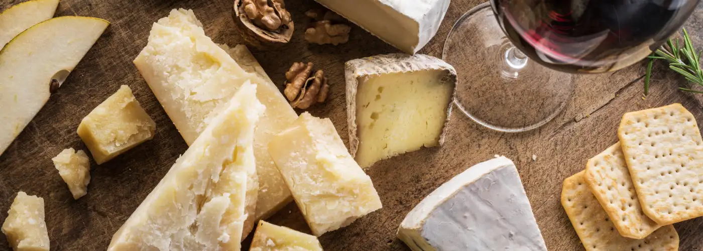 Cheese plate next to glass of red wine, as seen from above