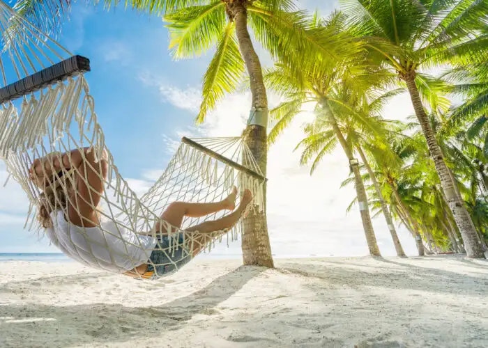 Person relaxing in hammock on beach