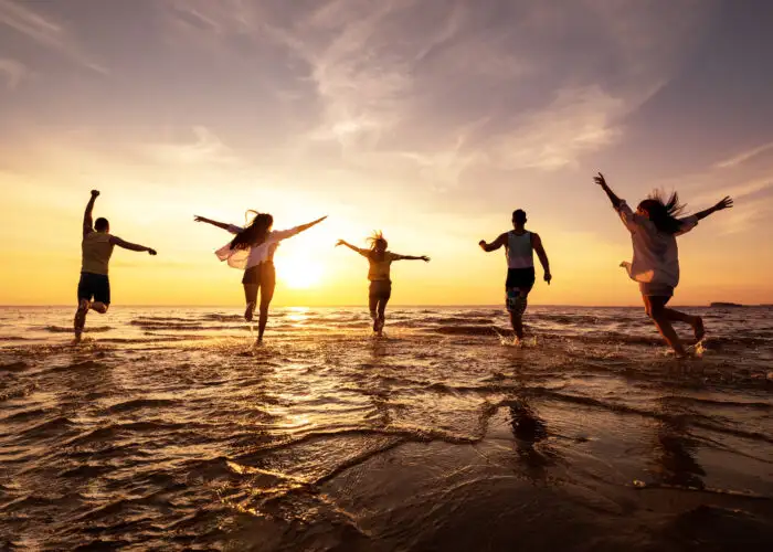 Silhouette of group of friends running into the ocean