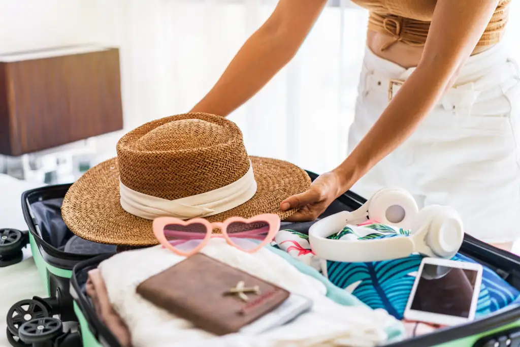 Close-up of woman packing suitcase on bed