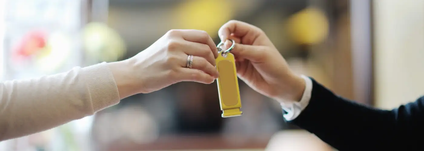 Close up of hotel concierge handing a room key off to a guest