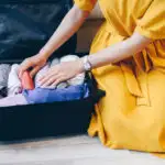 Close up of person in yellow dress packing a suitcase