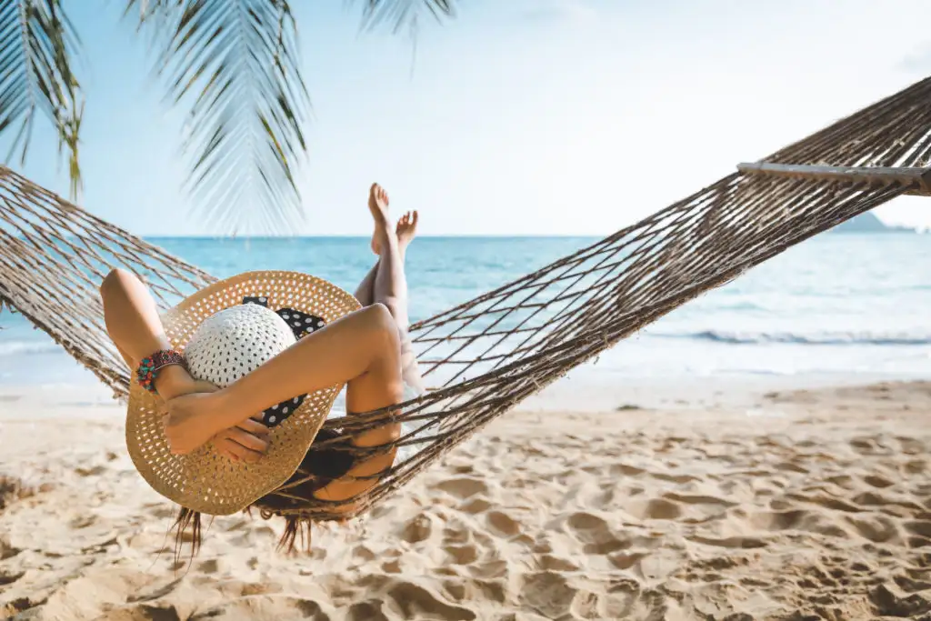 Woman lounging on a hammock on the beach looking out over the ocean