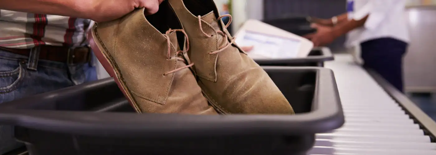 Close up of person placing shoes in a security bin at the airport security line