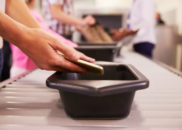 Close up of hands putting smartphone in security bin