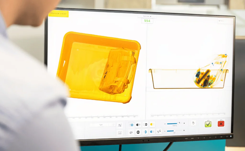 Airport security baggage screening. Security man looking at monitor scanning luggage through x-ray scanner