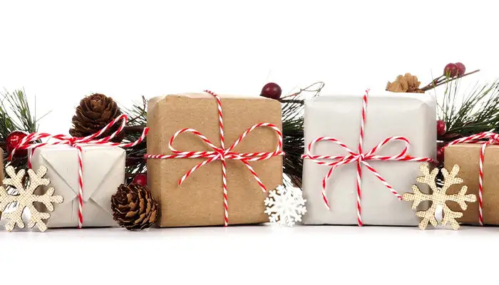 Christmas border with branches and rustic brown and white gift boxes isolated on a white background