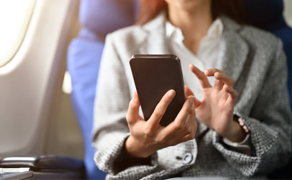 Close-up of a woman on a plane using a smartphone