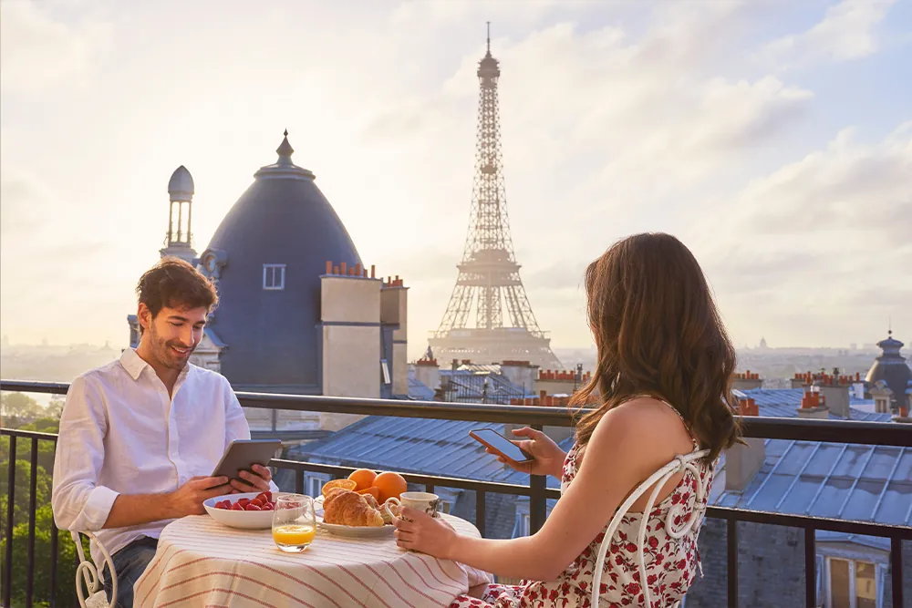 Travel, breakfast and couple in Paris with the Eiffel Tower on a terrace for romance or anniversary.