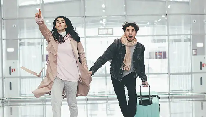 Young couple running through empty airport to catch flight