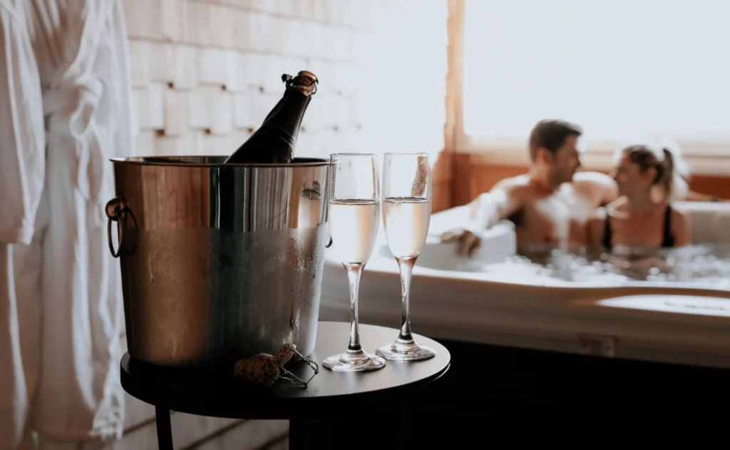 Couple Sitting in the hot tub with a bottle of champagne on ice and two flutes at The Wentworth, Jackson, New Hampshire 