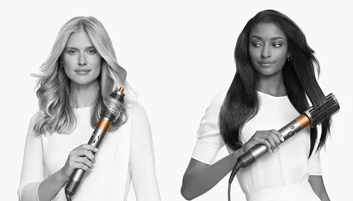 Four women using the Dyson Airwrap on their long hair, image in black and white