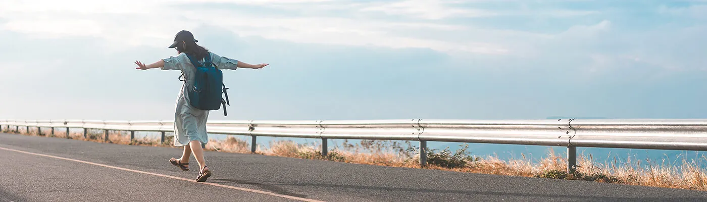 Woman walking along on side of road on a clear day