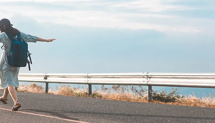 Woman walking along on side of road on a clear day