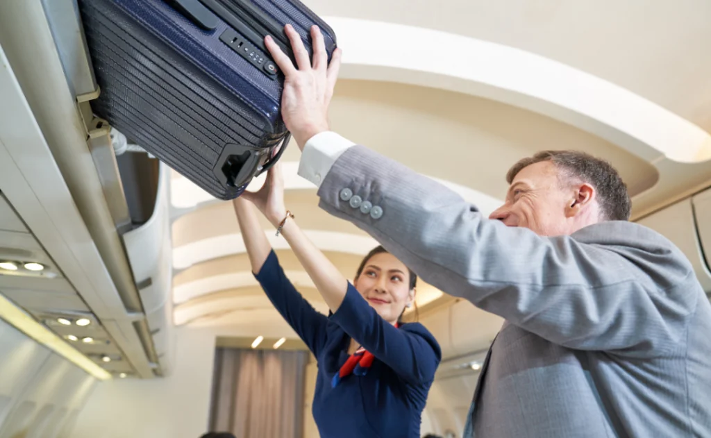 Flight Attendant helps businessman lift the luggage bag into cabin storage for travel