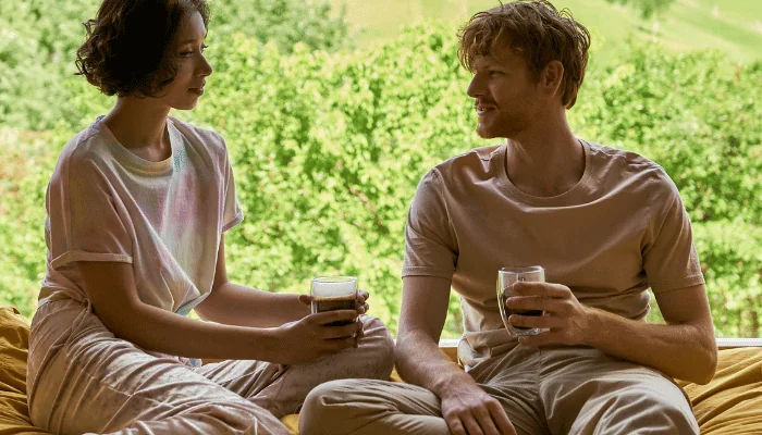 happy couple holding cups of morning coffee next to window with beautiful view, banner