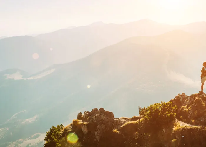 Mountain hiker with backpack tiny figurine stay on mountain peak with beautiful panorama