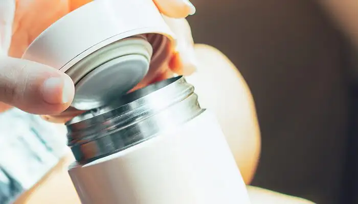 Close up of person's hands holding an insulated water bottle in a car