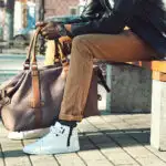 man holding weekender bag sitting bench city