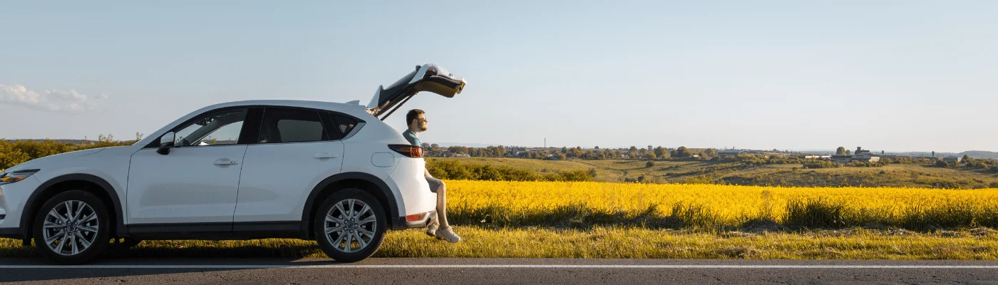 man sitting in car trunk enjoying view of sunset