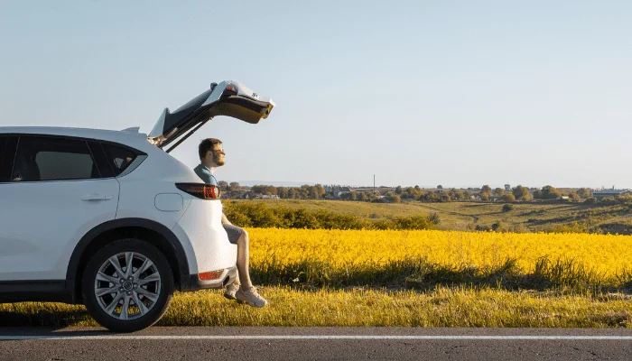 man sitting in car trunk enjoying view of sunset