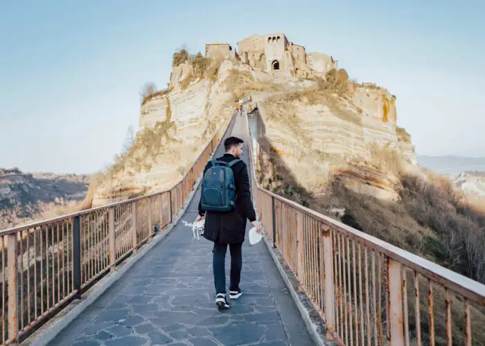 man walking up mountain wearing backpack