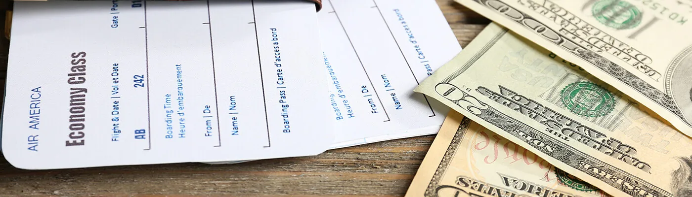 Airline tickets and cash on wooden table