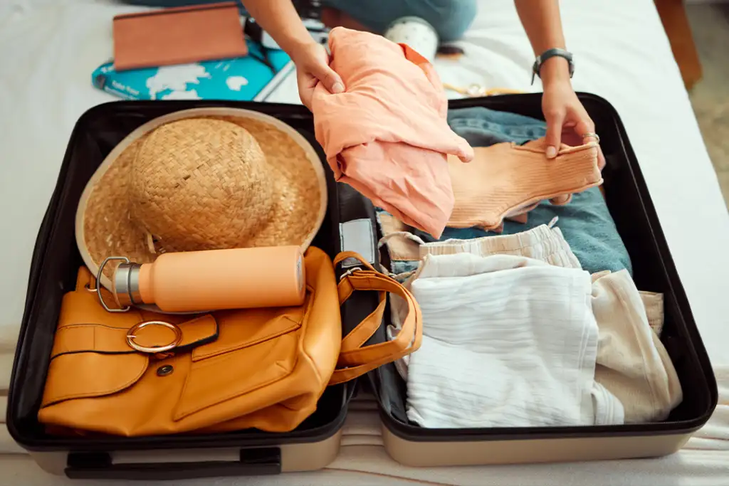 Hands, woman and suitcase on a bed for travel, adventure and summer vacation, packing and clothing. Hand, girl and luggage in a bedroom for travelling, abroad and break, relax and getaway preparation