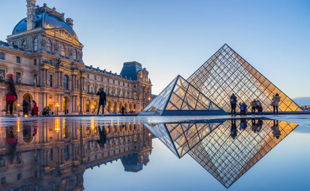 View of famous Louvre Museum with Louvre Pyramid at evening at sunset in Paris France