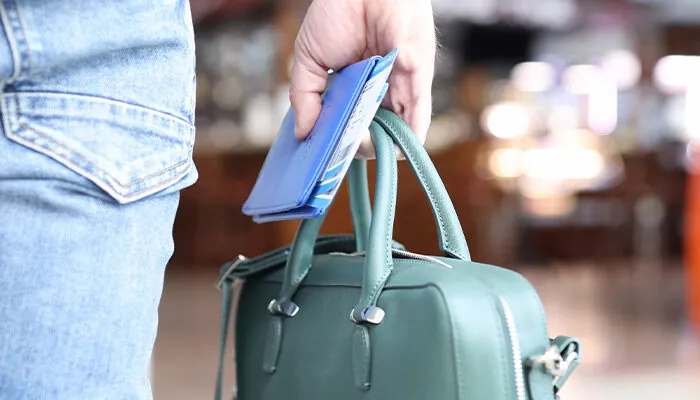 Man holds bag with a passport and tickets in his hand while standing at airport