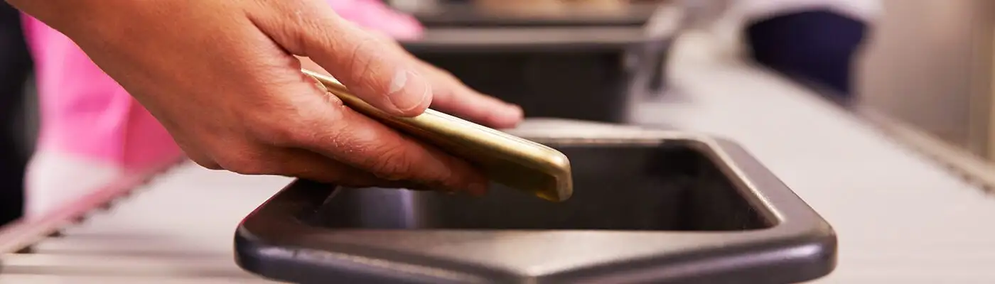 Person placing phone in bin for TSA airport security screening