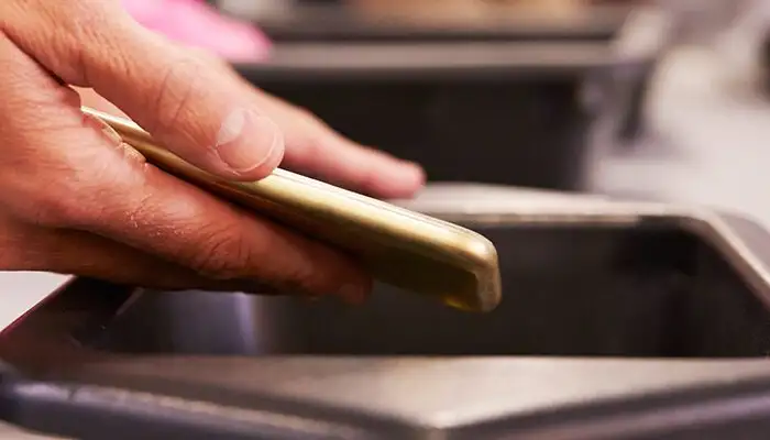 Person placing phone in bin for TSA airport security screening