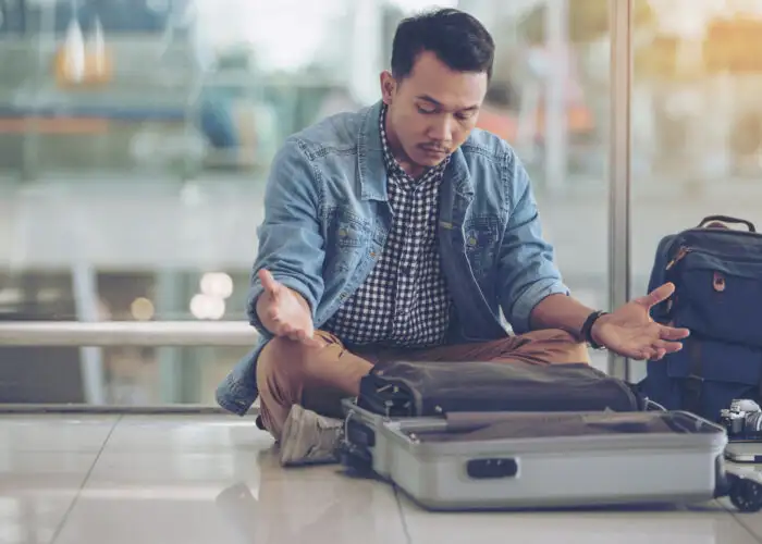 man looking at empty suitcase worried