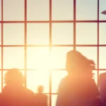 Silhouettes of people in a crowded airport at sunset